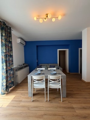 Un comedor moderno con una pared azul de acento, una mesa de comedor preparada para cuatro personas y una lámpara de techo.