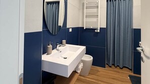 Une salle de bain avec un lavabo blanc, un miroir, un porte-serviettes et un rideau de douche.
