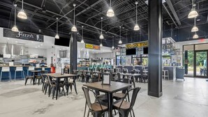 Een ruime binnenzone met meerdere tafels en stoelen, een balie met een menukaart, en een bord met de tekst 'Fuzzy's Restaurant'.
