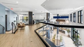 Een ruime, overdekte ruimte met een modern design, met een zithoek met banken, een trap en uitzicht op een eetgedeelte.