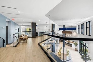 A spacious indoor area with a modern design, featuring a seating area with sofas, a staircase, and a view of a dining area.
