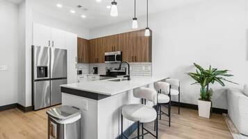 A modern kitchen with stainless steel appliances, a central island with bar stools, and a wooden accent wall.