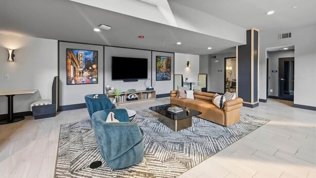 Een moderne woonkamer met een flatscreen televisie, twee banken, een salontafel en kunstwerken aan de muur.