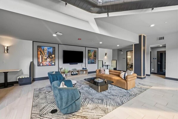 A modern living room with a flat-screen TV, two sofas, a coffee table, and artwork on the walls.