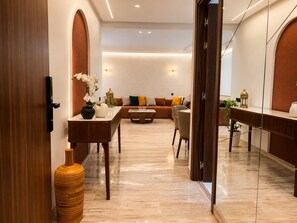 A modern interior with a wooden door, a dining area with a table and chairs, a sofa with cushions, and a large mirror. - Studio Chic & Luxueux • Centre Casablanca (Dar-el-Beida)