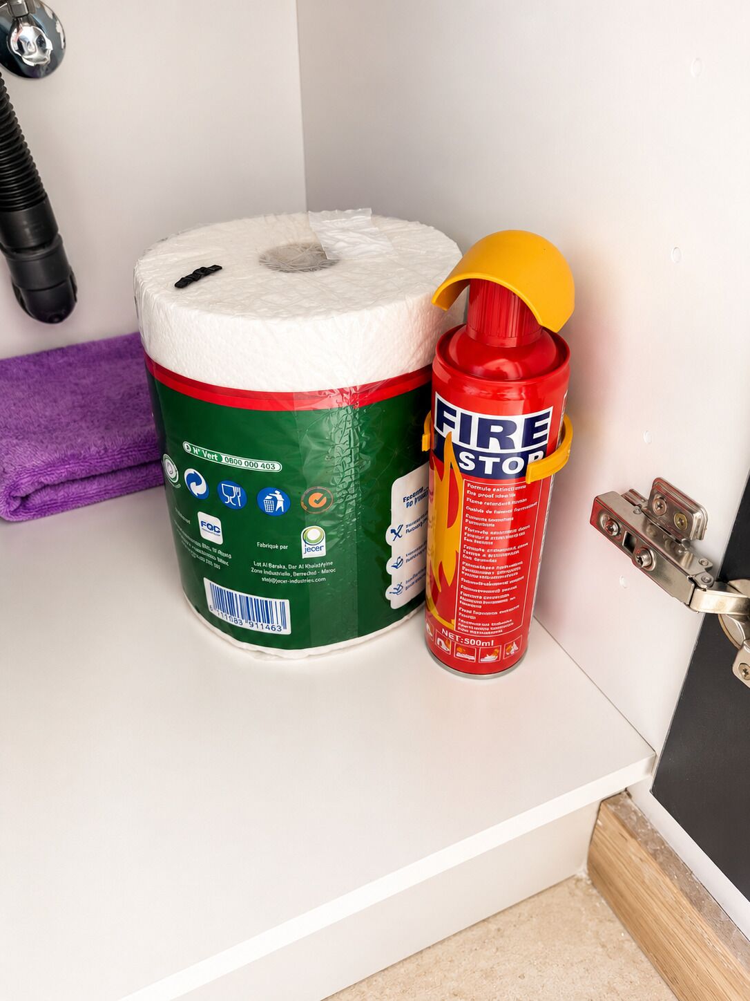 WC-paperirulla, palosammutin ja violetti pyyhe valkoisella alustalla.