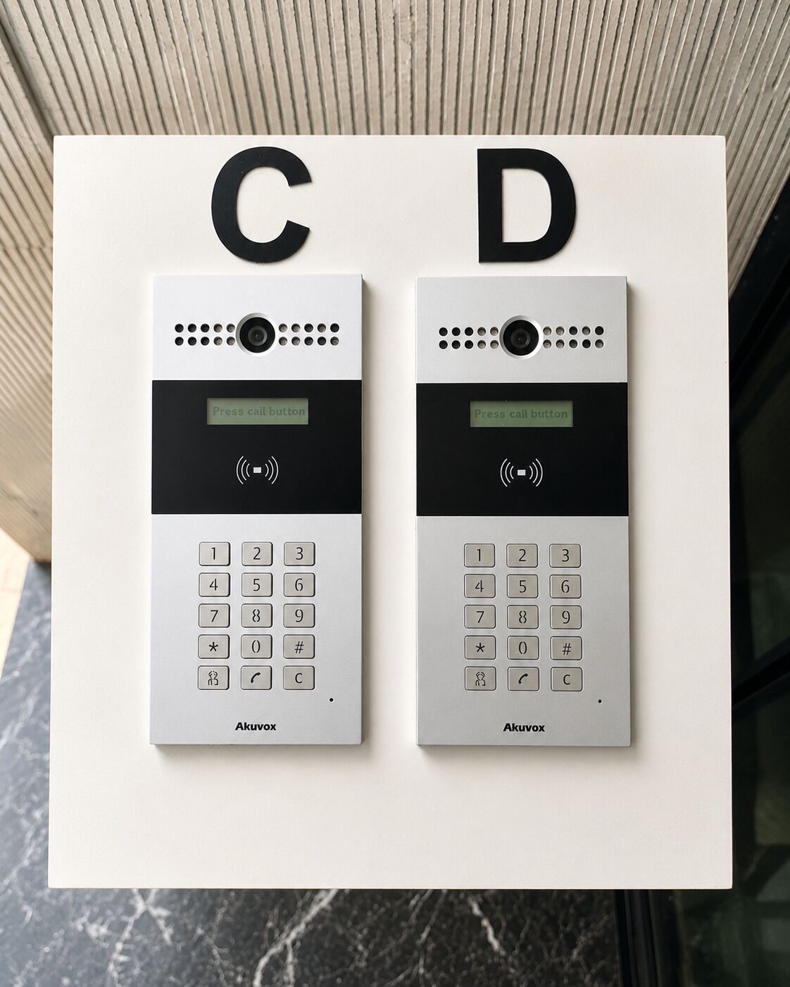 Deux systèmes d’interphonie muraux, identifiés par les lettres « C » et « D », équipés d’un clavier et d’un bouton d’appel.