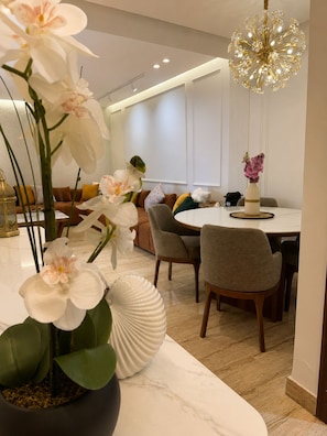Uma área de jantar moderna com uma mesa de mármore, cadeiras e um lustre decorativo.
