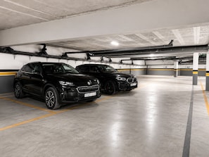 A parking garage with two black cars parked in designated spaces. - Studio Chic & Luxueux • Centre Casablanca (Dar-el-Beida)