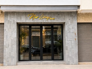 A modern building facade with a large glass entrance and a sign reading 'New Living House'. - Studio Chic & Luxueux • Centre Casablanca (Dar-el-Beida)