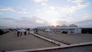 A desert landscape with multiple white tents and a clear sky. - Experience the Best Jaisalmer Desert Safari & Luxury Camp Stay (Jaisalmer)