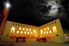 Un edificio con diverse finestre illuminate e la luna nel cielo.