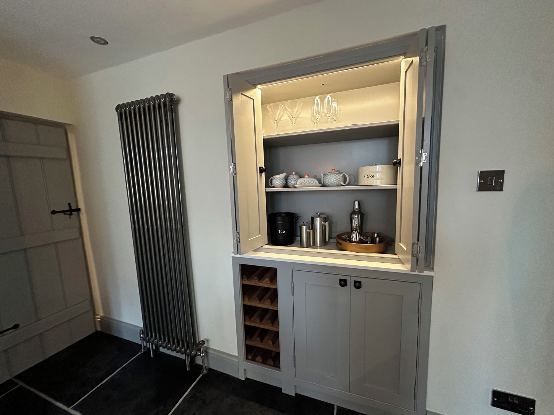 Eine Küche mit integriertem Weinkühlschrank, einem Heizkörper und einem Schrank voller Küchenutensilien.