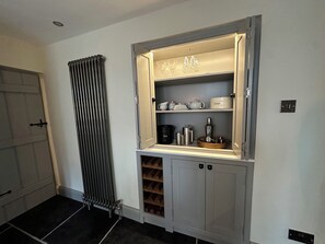 A kitchen with a built-in wine rack, a radiator, and a cabinet with kitchenware. - La'al Kirkstone Brow (Ambleside)