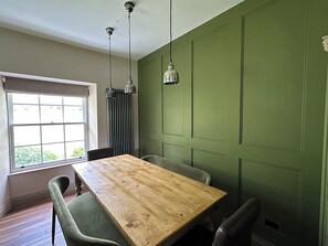 A room with a wooden table, two chairs, a window with blinds, and a green wall. - Kirkstone Brow (Ambleside)