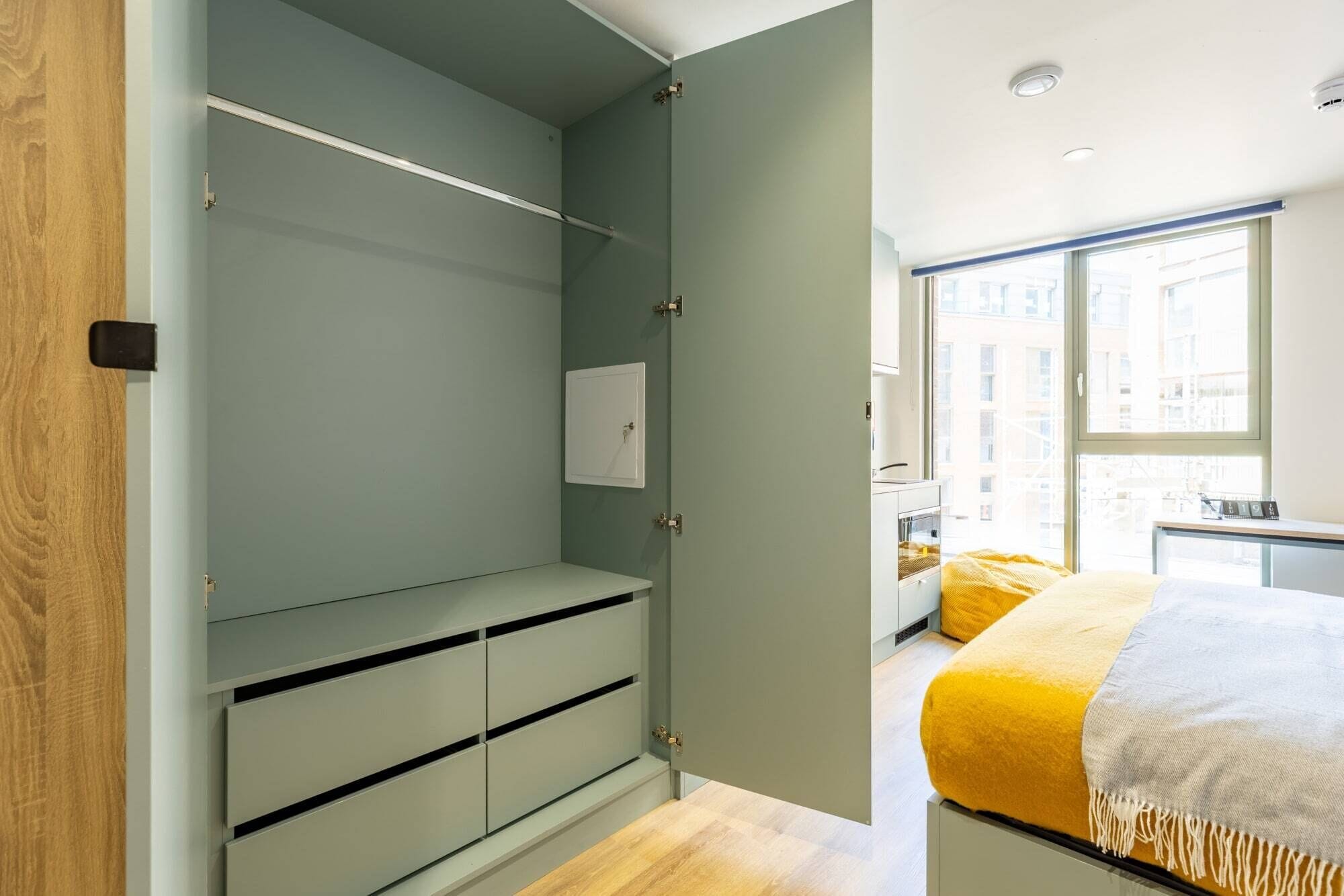 Un dormitorio moderno con cama, ventana y vistas a edificios.