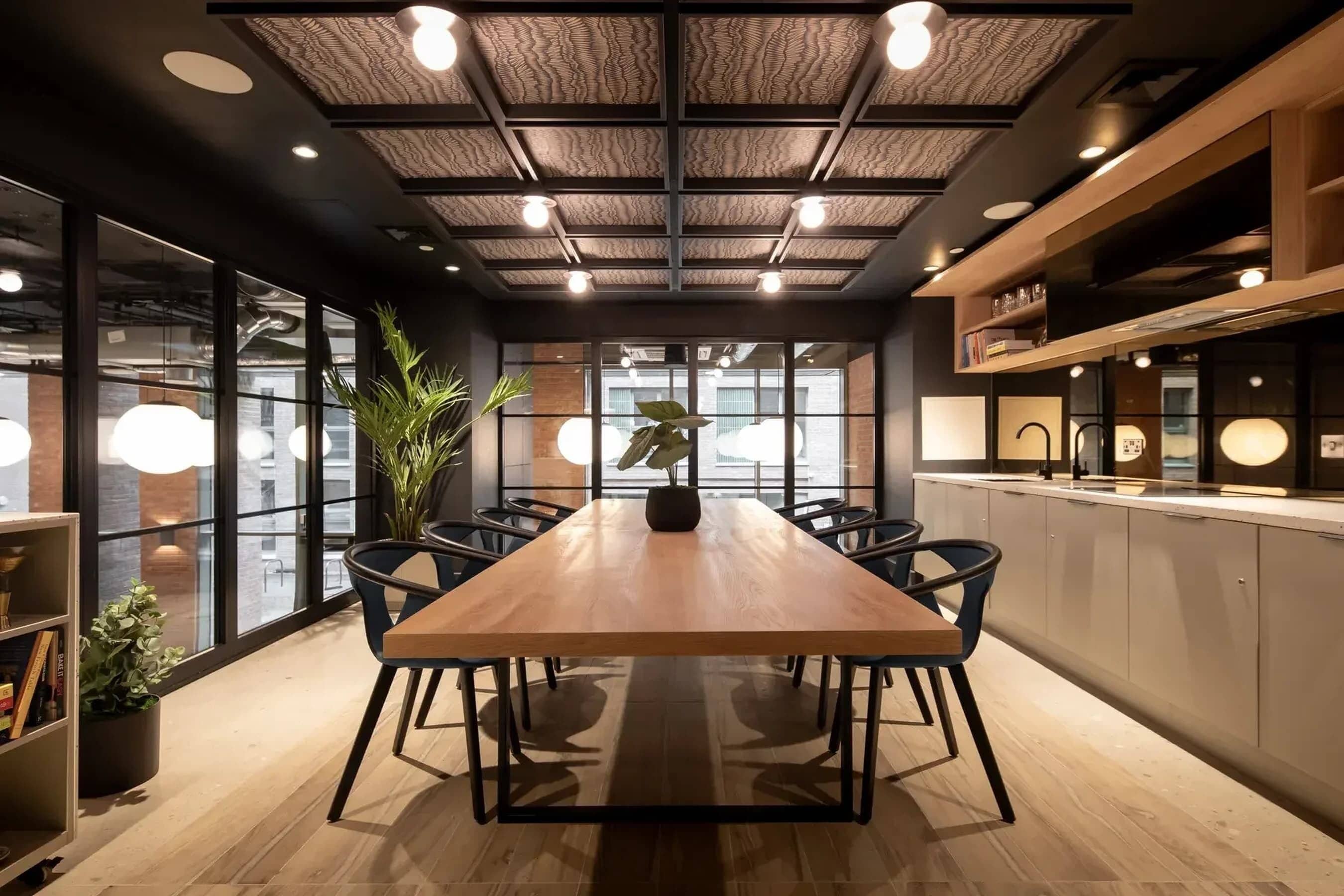 Een vergaderzaal met een lange tafel, stoelen, een kamerplant en een uitzicht door grote ramen.