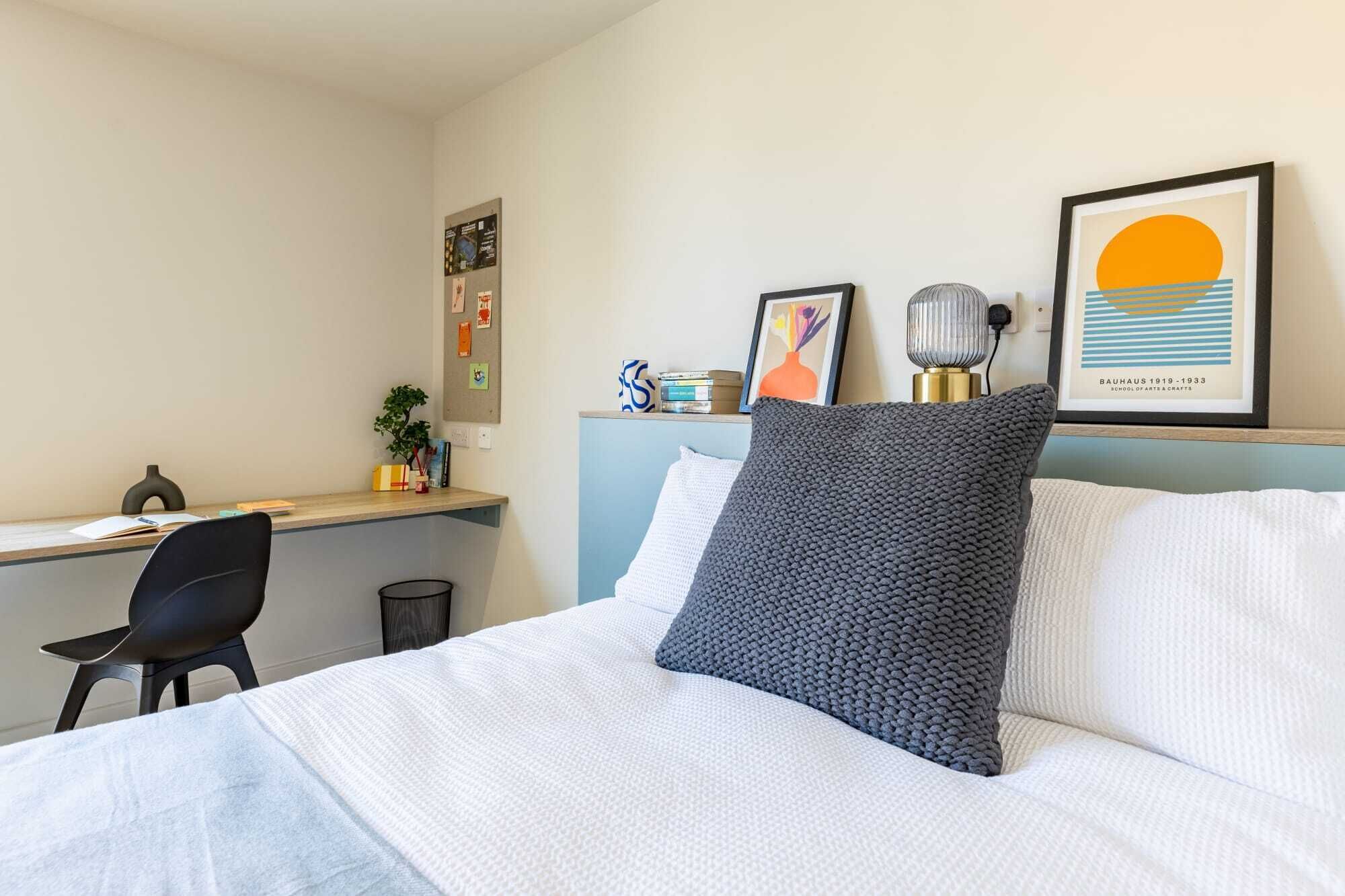 A neatly arranged hotel room with a bed, a desk, and a chair.