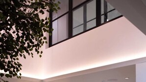 A modern reception area with a wooden reception desk, a large circular wall feature, and a seating area with a bench and chairs. - Student Only Centre Court (Nottingham)