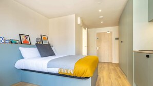 A modern bedroom with a bed, a bedside table, a nightstand, a wardrobe, and a door. - Student Only Centre Court (Nottingham)