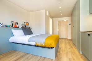 A modern bedroom with a bed, a bedside table, a nightstand, a wardrobe, and a door. - Student Only Centre Court (Nottingham)