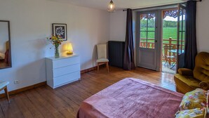 Ein Schlafzimmer mit Bett, Schminktisch, Stuhl und Blick auf einen Balkon.