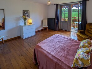 Ein Schlafzimmer mit Bett, Schminktisch, Stuhl und Blick auf einen Balkon.