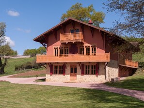 Eine zweistöckige Chalet mit Balkon, Stein Fundament und einem Weg zum Eingang.