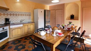 Eine kompakte Küche mit Essbereich, ausgestattet mit einer gefliesten Spritzschutzwand, einem Kühlschrank, einer Kaffeemaschine und einem für das Frühstück gedecktem Tisch.