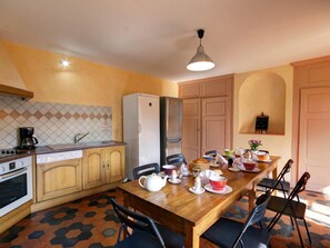 Eine kompakte Küche mit Essbereich, ausgestattet mit einer gefliesten Spritzschutzwand, einem Kühlschrank, einer Kaffeemaschine und einem für das Frühstück gedecktem Tisch.