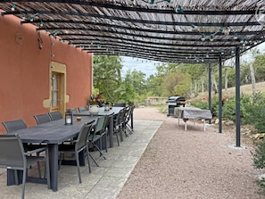 An outdoor patio with a table and chairs, a grill, and a pergola with string lights. - Spacious house in the heart of the Loire - 15 guests (Pouilly-sous-Charlieu)