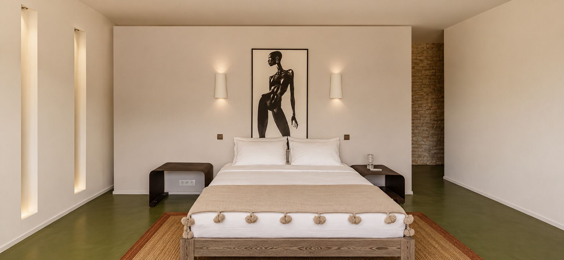A modern bedroom with a large bed, two bedside tables, and a wall-mounted artwork.