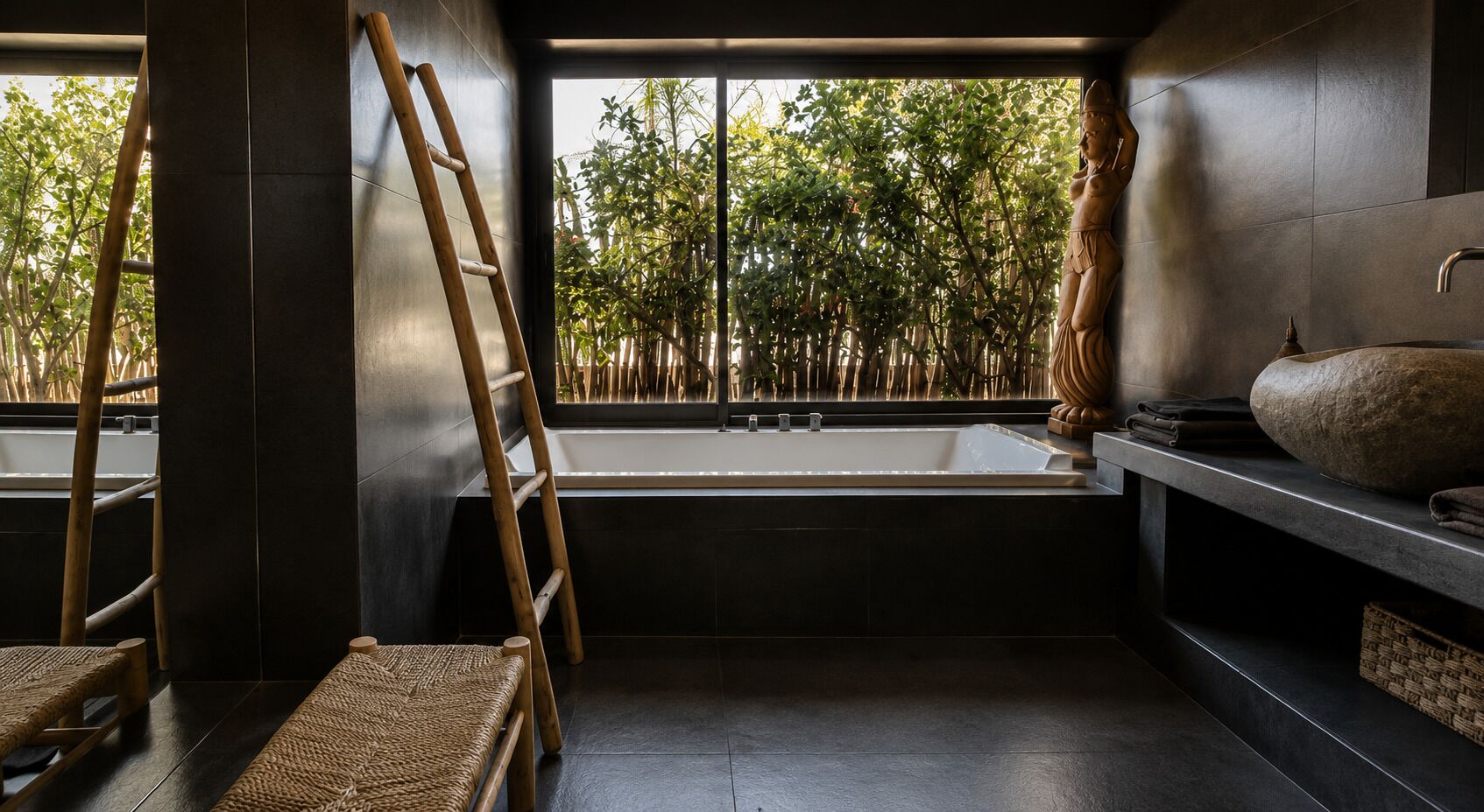 Un baño con bañera, una escalera de madera y vistas a bambú.