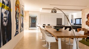 A modern dining area with a wooden table, white chairs, and a central island. - NAUSIKAA: 4-bedroom villa with concierge, 420 m² in Essaouira, with a 20-meter pool. (Essaouira)