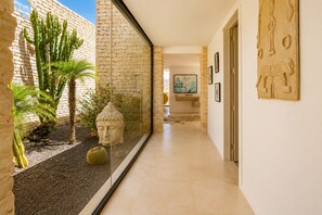 A hallway with a glass partition, a Buddha statue, and a cactus. - NAUSIKAA: 4-bedroom villa with concierge, 420 m² in Essaouira, with a 20-meter pool. (Essaouira)