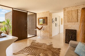 Ein modernes Interieur mit Steinwand, Holztür, rundem Tisch, Zebrafellteppich, Sofa und Kamin.