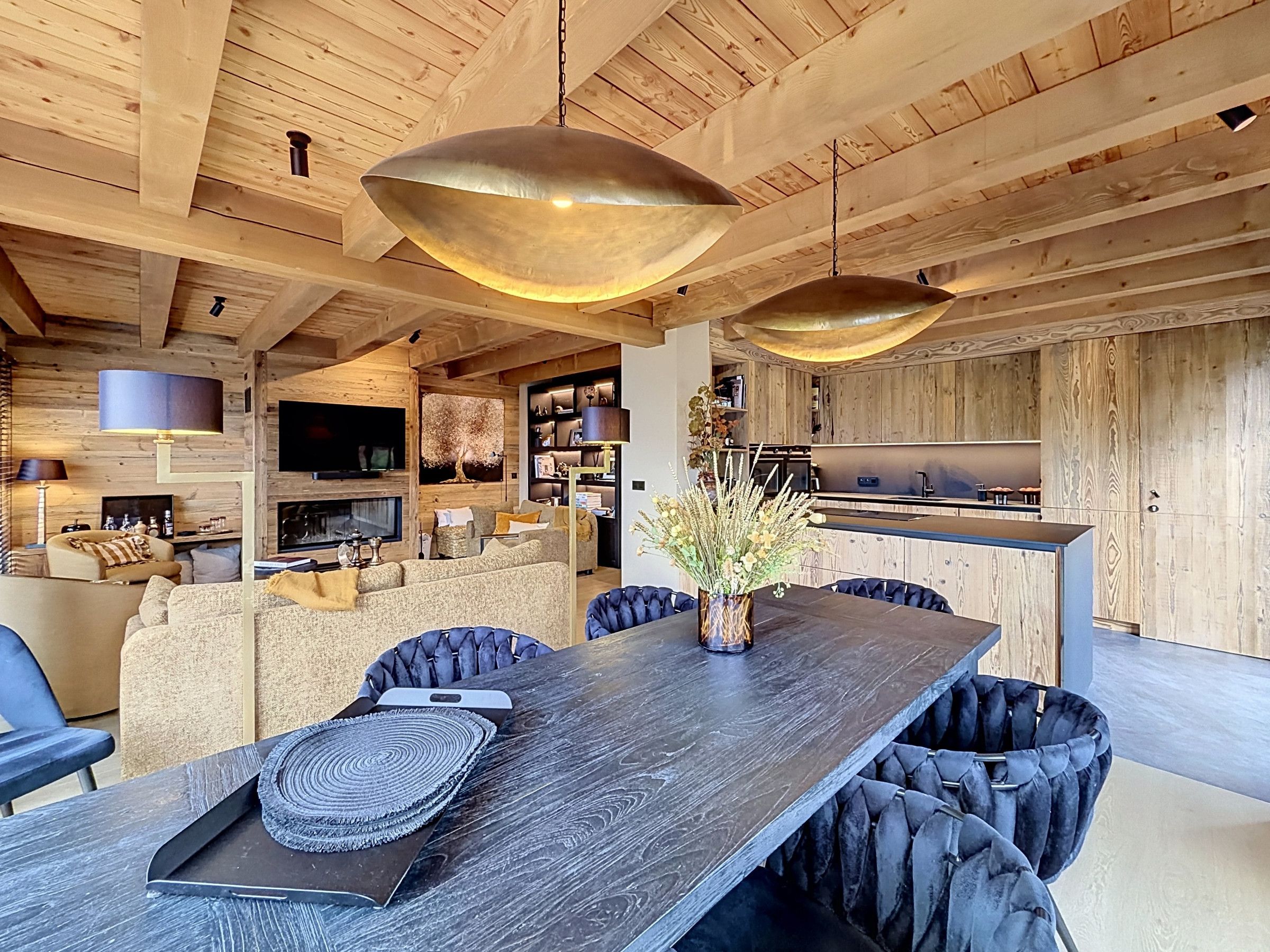 Ein modernes Interieur mit Essbereich, Holzbalkendecke und Küche.