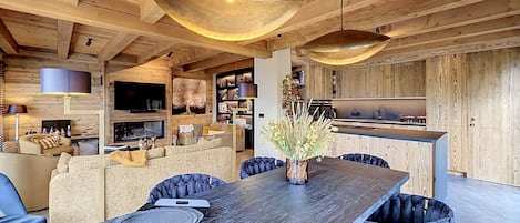Un intérieur moderne comprenant un coin repas, des poutres en bois au plafond et une cuisine.