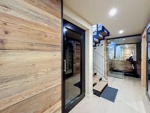 Ein modernes Interieur mit einer Holzwand, einer Glastür und einer Treppe mit Metallgeländer.