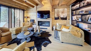 A cozy living room with a fireplace, comfortable seating, and a bookshelf. - Stunning half-chalet in the village centre - 8 guests (Combloux)