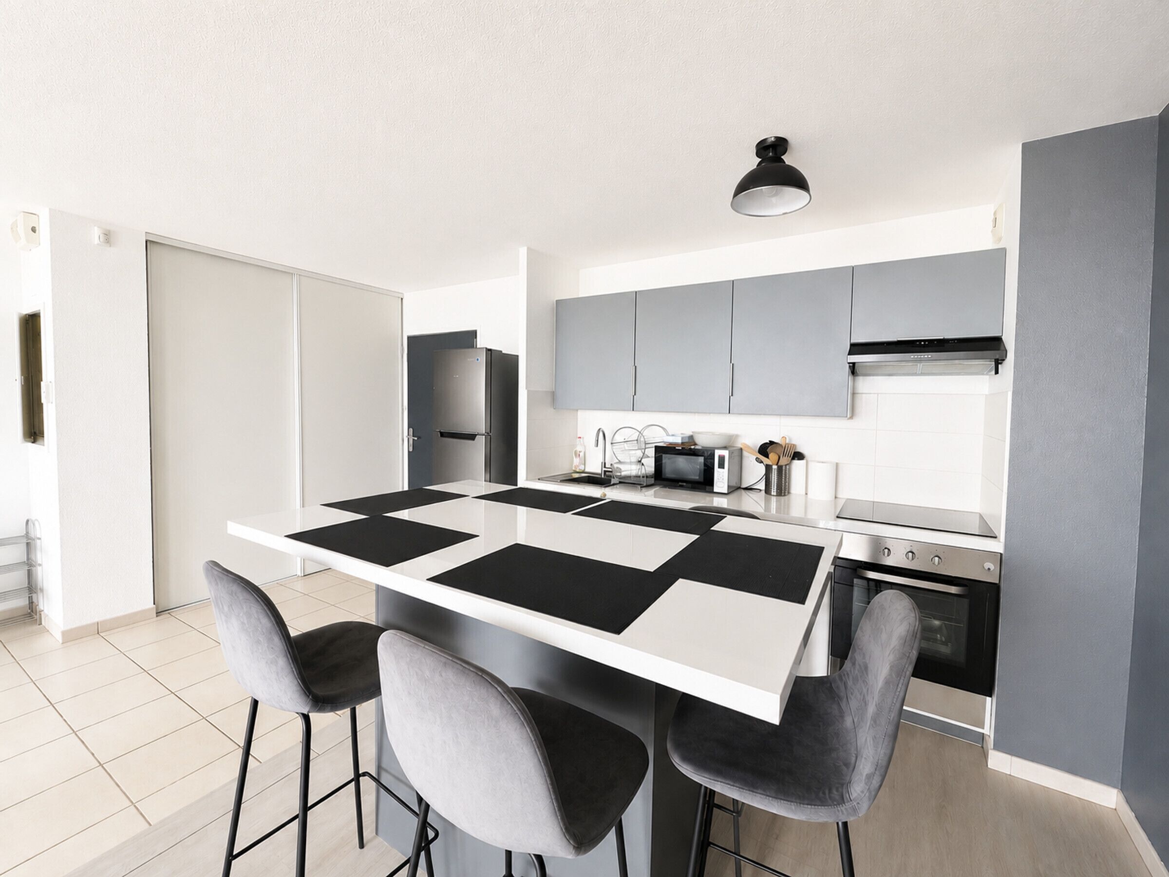 A modern kitchen with a central island, bar stools, a microwave, and a built-in oven.