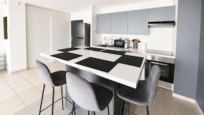 Uma cozinha moderna com uma ilha central, banquetas, micro-ondas e forno embutido.