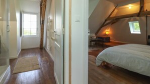 Un dormitorio con techo inclinado, cama, escritorio y ventana.