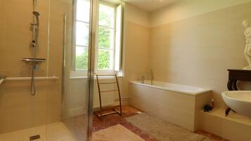 Ein Badezimmer mit Dusche, Badewanne, Toilette und Fenster.