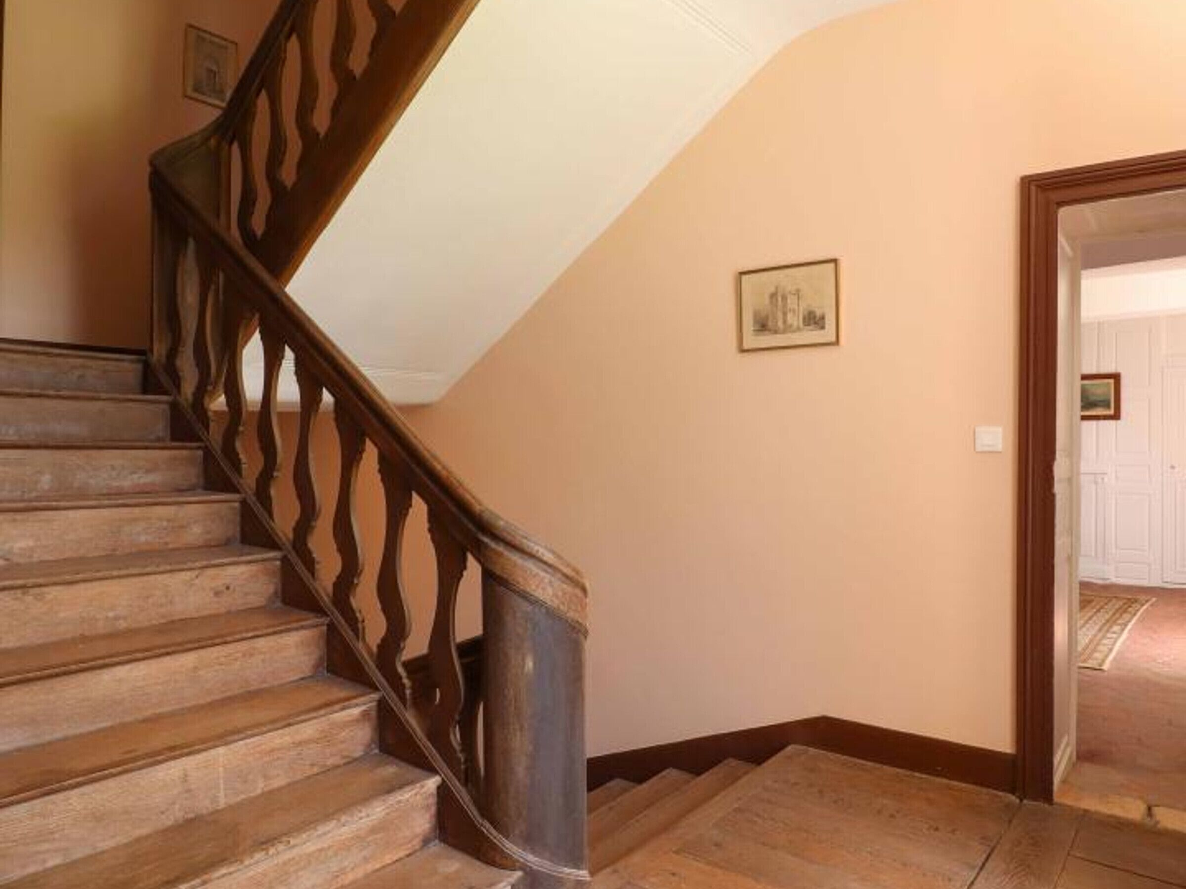 Een houten trap met een decoratieve balustrade die uitkomt op een plateau.