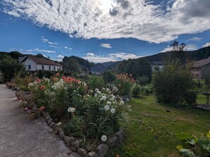 Un paysage rural avec un jardin, un sentier en pierre et des maisons traditionnelles.