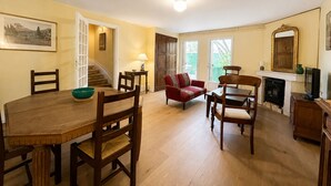 Uma sala de jantar com uma mesa e cadeiras de madeira, um sofá vermelho e uma lareira.