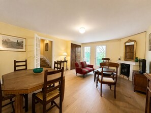A dining area with a wooden table and chairs, a red sofa, and a fireplace.
