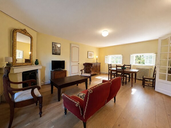A living room with a fireplace, television, dining table, and red sofa.
