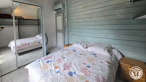Ett rum med två våningssängar, en garderob med spegeldörrar och en säng med ett blommigt överkast.